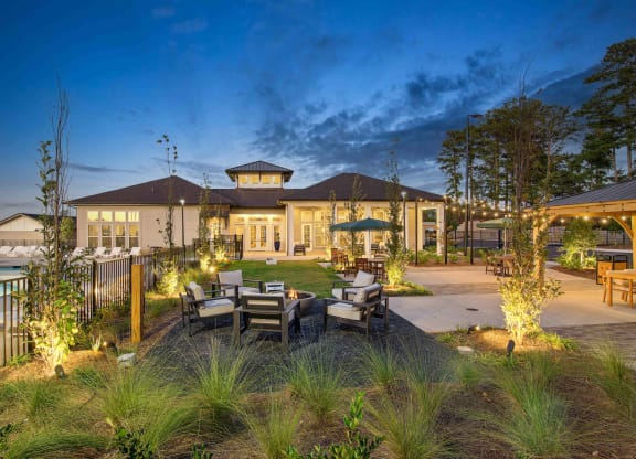 a backyard with tables and chairs and a pool at night