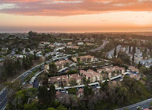 A sunset view of a residential area with houses and trees.