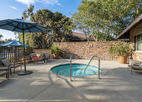A pool with a blue umbrella and a stone wall.