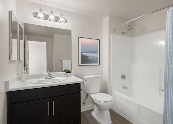 A bathroom with a white toilet, sink, and shower.