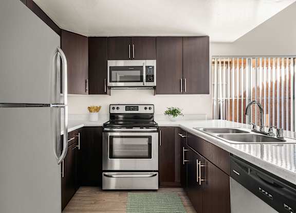 A modern kitchen with dark brown cabinets and stainless steel appliances.