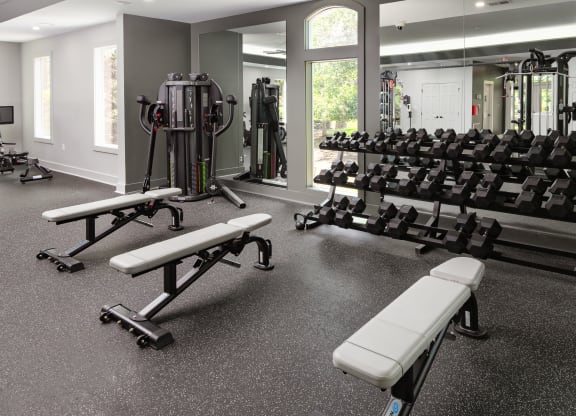 a gym with weights and benches in the center of the room