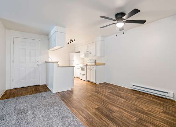 A room with a ceiling fan and a rug on the floor.