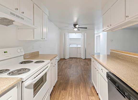 A kitchen with white appliances and wooden floors.