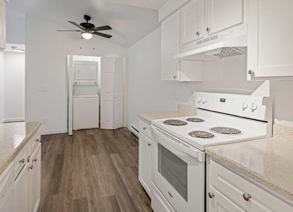 A white kitchen with a fan and a stove top oven.