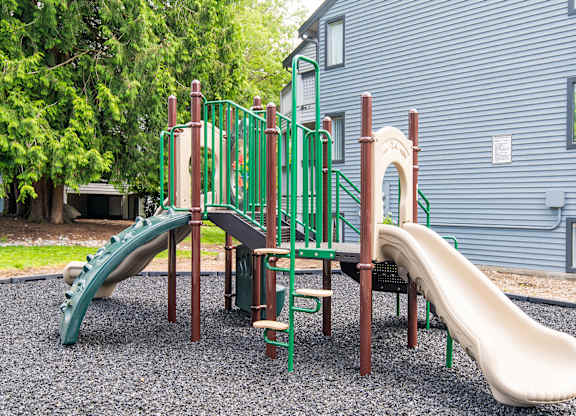 A playground with a green slide and a brown slide.