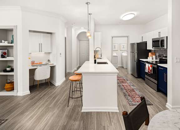 an open kitchen and living room with a large island and a black refrigerator