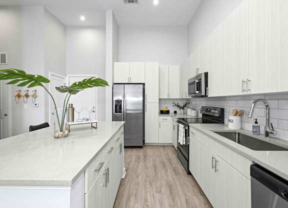 A modern kitchen with white cabinets and a marble countertop.