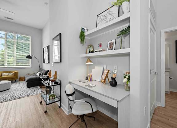 A white desk with a chair and a shelf with green plants on it.