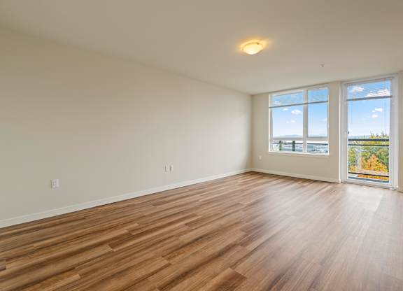 A room with wooden flooring and a large window overlooking the ocean.