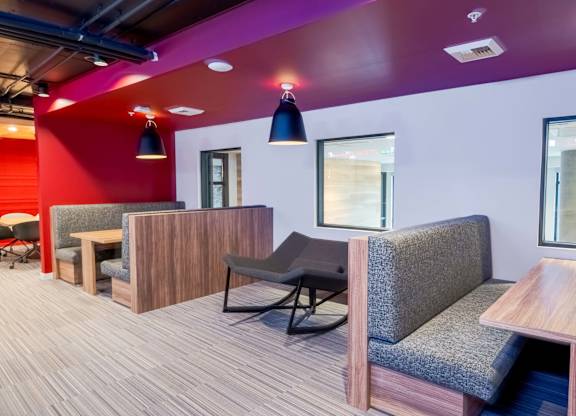 A modern office space with a red accent wall and wooden furniture.at Axle, Seattle 