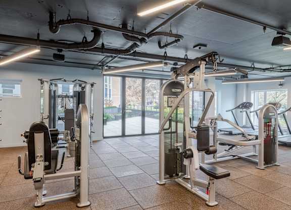 A gym with a variety of equipment including a leg press machine and a treadmill.at Axle, Seattle 