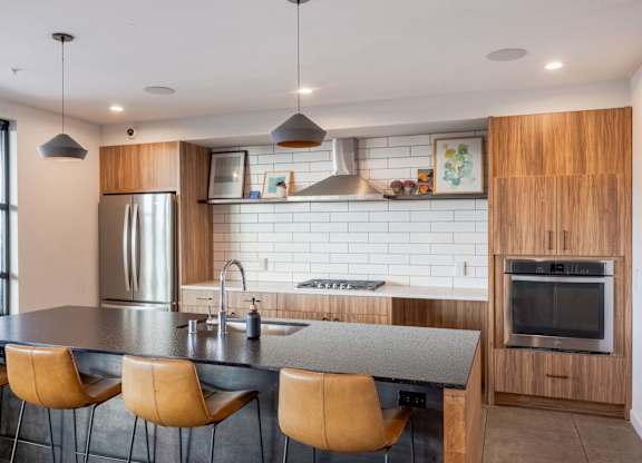 A modern kitchen with a stainless steel refrigerator, a wooden cabinet, and a black countertop.at Axle, Seattle, 98119 