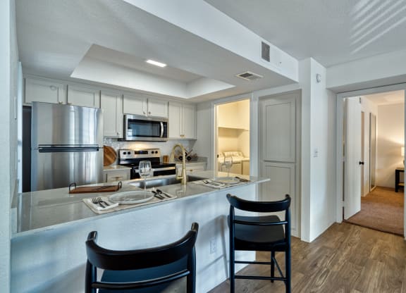 a kitchen with a bar and two chairs in front of a