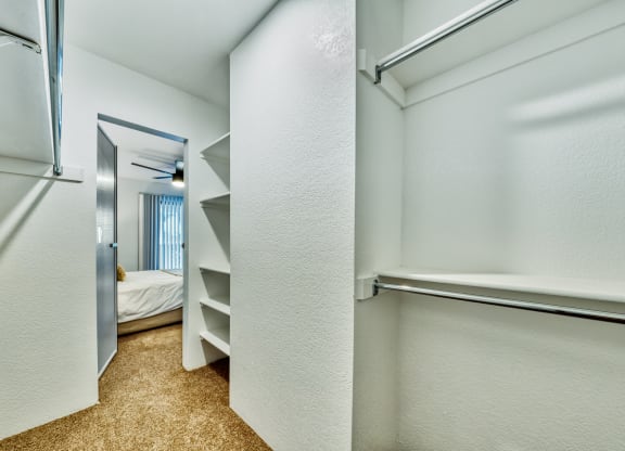 a walk in closet with shelves and a mirror in a room with a bed