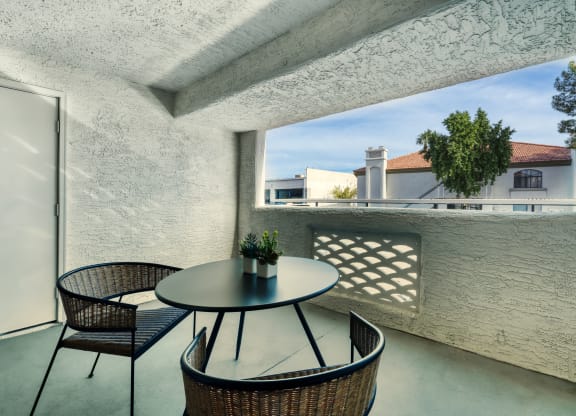 a balcony with a table and chairs and a window