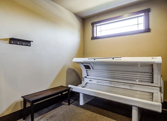 A white piano with a bench in front of it is in a room with a window.