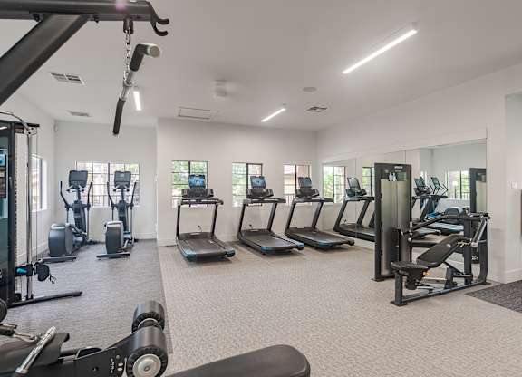 A gym with a variety of equipment including treadmills, weights, and exercise machines.