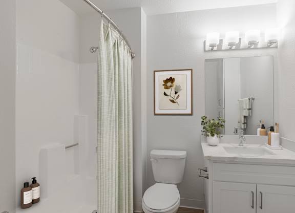 A white bathroom with a toilet, sink, and shower.