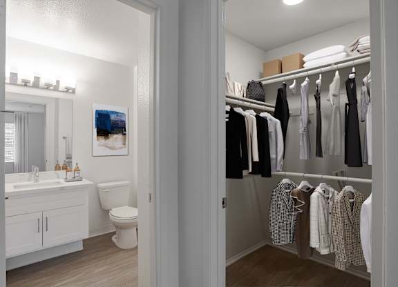 A white bathroom with a toilet, sink, and a closet with clothes.