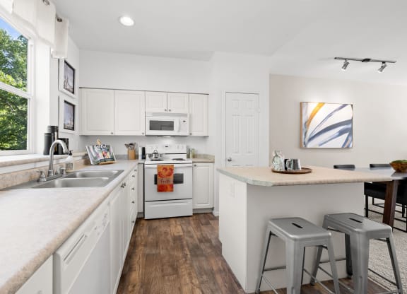 a kitchen with white cabinets and a large window