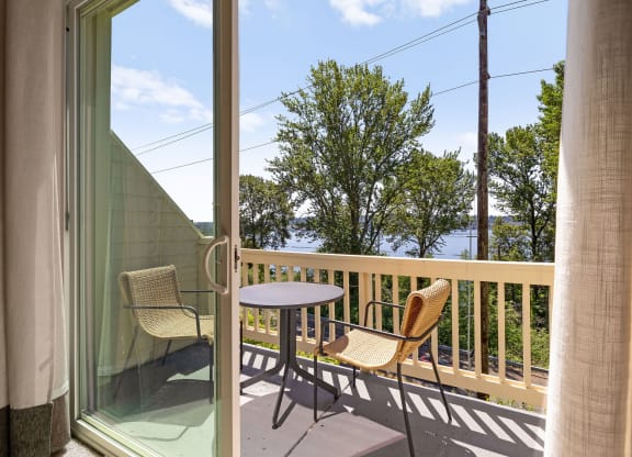 a balcony with a table and two chairs and a view of the water