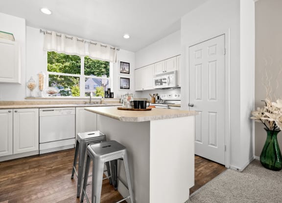 a kitchen with white cabinets and a white island with two stools