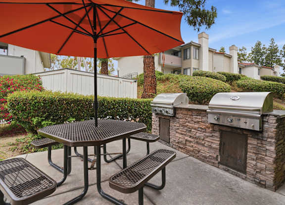 A patio with a table, chairs and an umbrella.