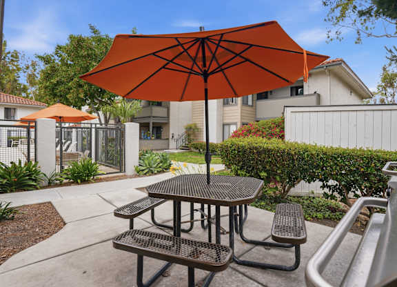 A patio with a table and chairs under an orange umbrella.