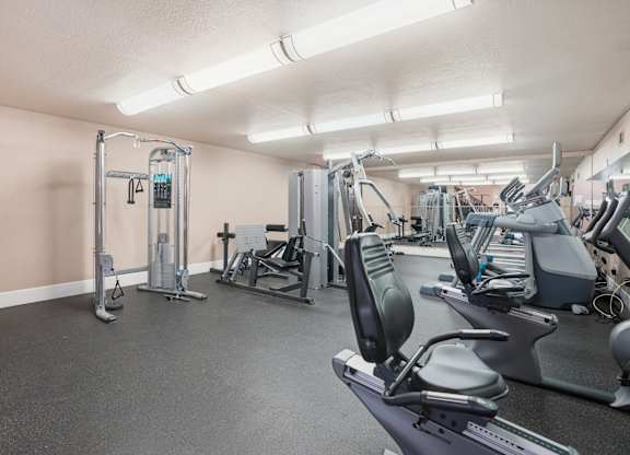 A gym with a variety of equipment including treadmills, weights, and exercise machines.