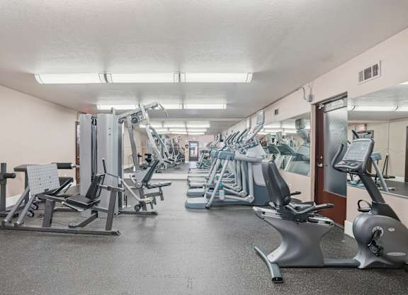 A gym with a variety of equipment including treadmills, stationary bikes, and weight machines.