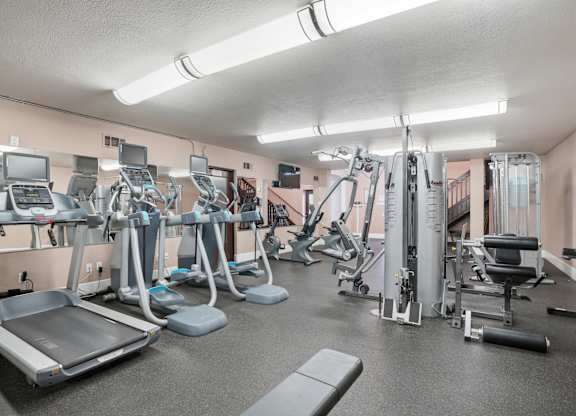 A gym with a variety of equipment including treadmills, weights, and exercise machines.