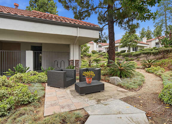 A patio with a table and chairs is surrounded by a garden.