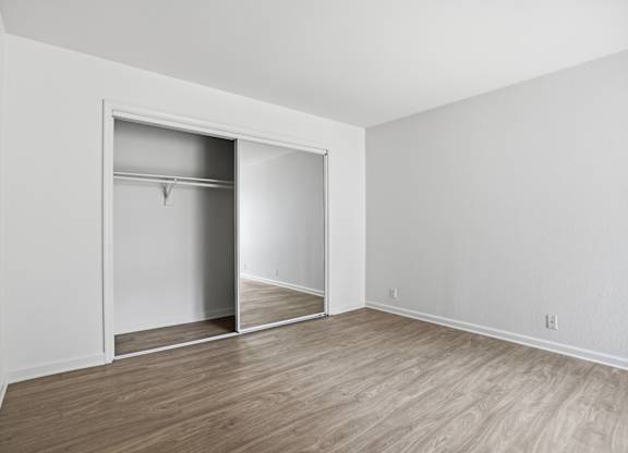 A room with a white wall and a white closet with a mirror.