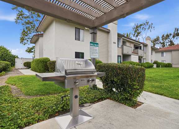 A barbecue grill is in the foreground of a residential area.