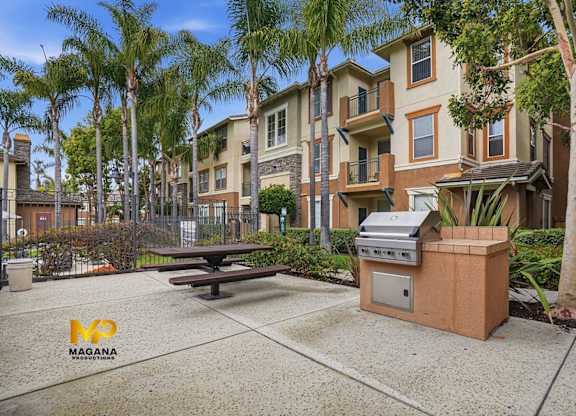 A Magana apartment complex with a picnic table and BBQ grill in the courtyard.