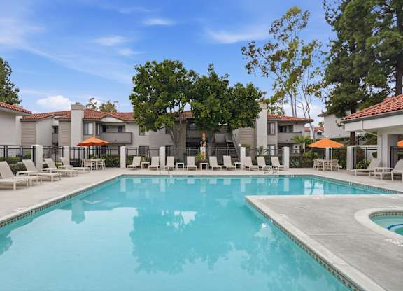A large swimming pool surrounded by lounge chairs and trees.