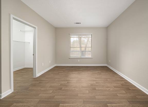an empty living room with wood flooring and a window