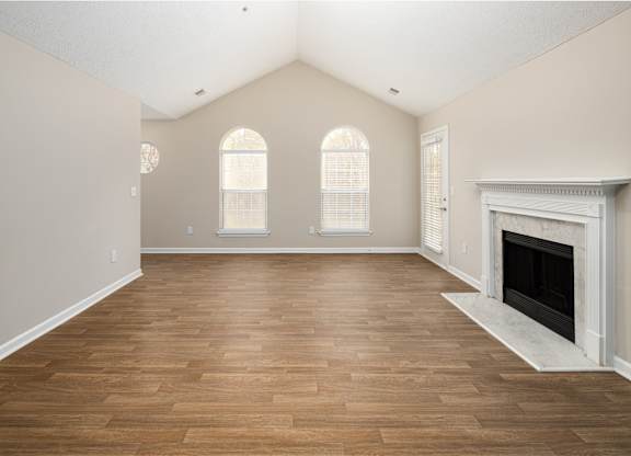 an empty living room with a fireplace and wooden floors