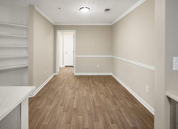 an empty room with wooden floors and white shelves