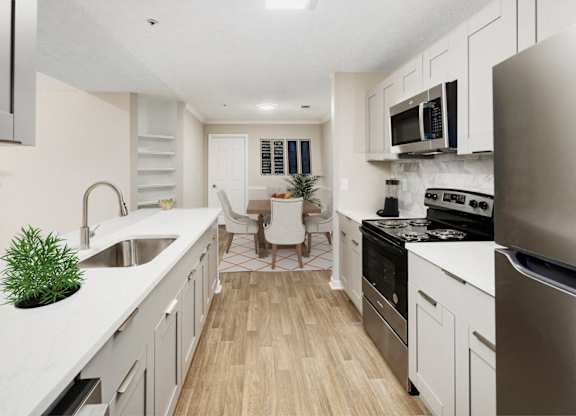 an open kitchen and living room with white cabinets and stainless steel appliances