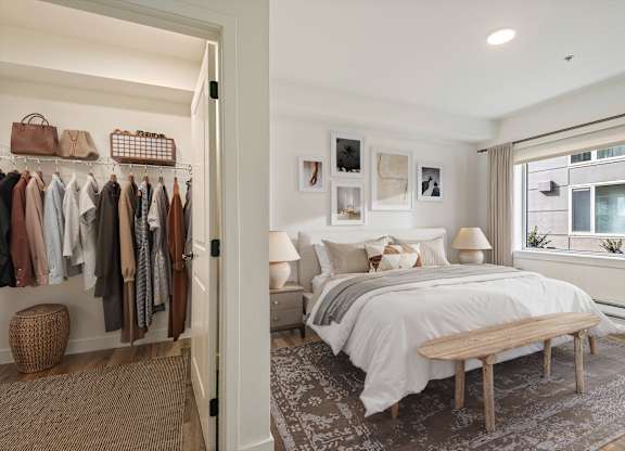 A bedroom with a bed, a bench, and a closet with clothes.