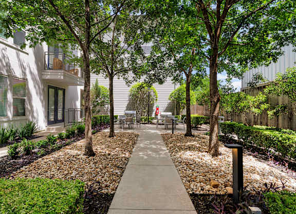 A walkway in a landscaped area with trees and shrubs.