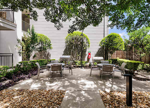 A patio with chairs and a table surrounded by a stone border.