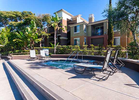 A pool with a table and chairs in front of a building.