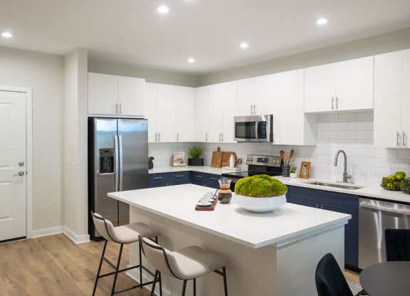 a kitchen with a white counter top and a stainless steel refrigerator