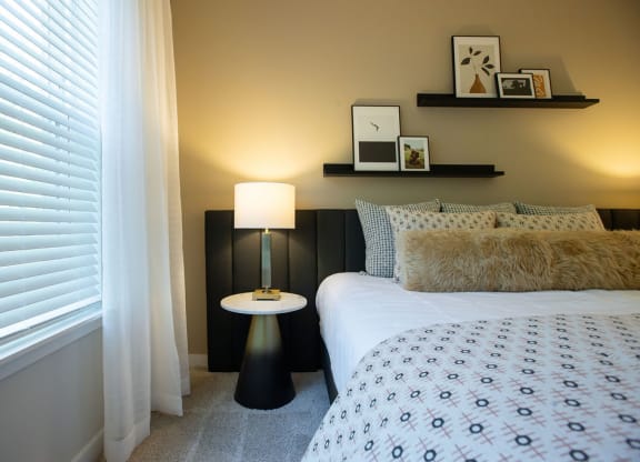 a bedroom with a bed and a lamp and a window
