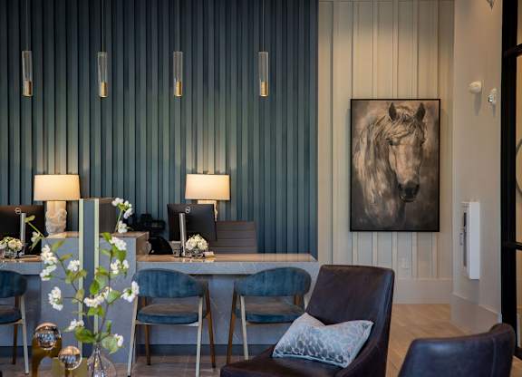 a living room with blue chairs and a table with a horse painting
