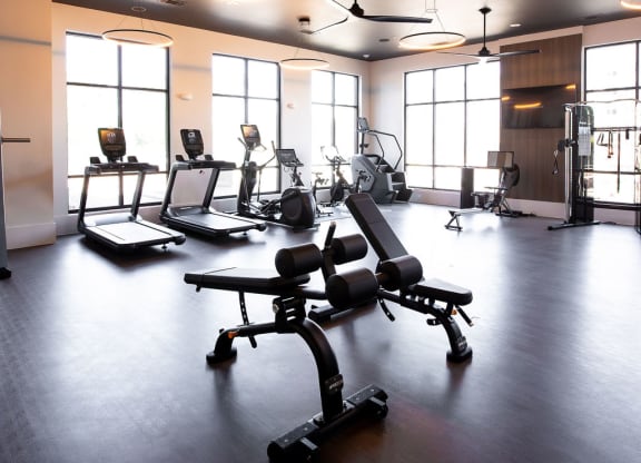 a fitness room with weights and chairs in it