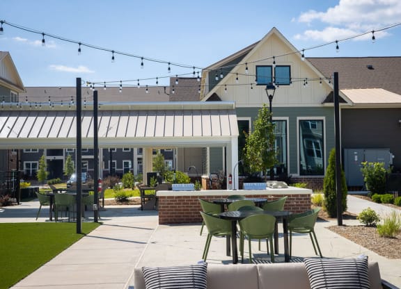 a patio with tables and chairs in front of a house